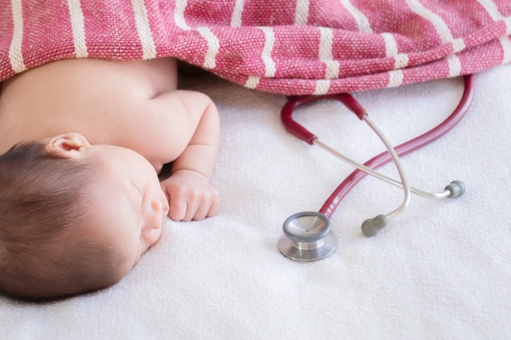 A newborn baby lies gently beside a stethoscope, symbolizing the spectrum of birth injuries