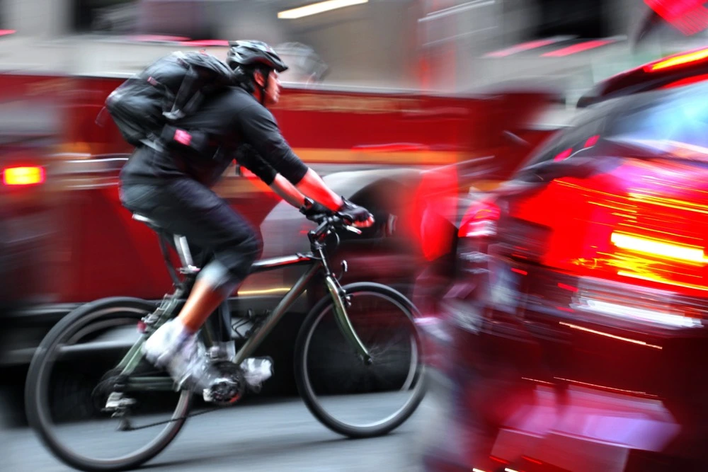 A reckless cyclist weaving through bustling traffic embodies the concept of Contributory Negligence, highlighting the shared responsibility in personal injury incidents