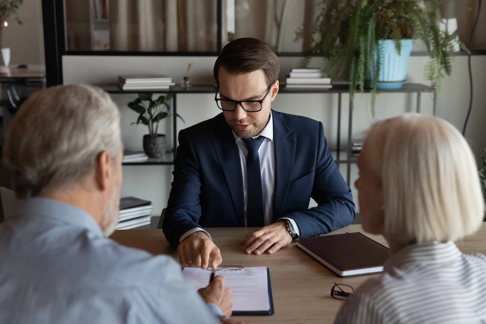 In a Baltimore law office, a medical malpractice lawyer leans forward intently, explaining the intricacies of filing a medical malpractice claim to concerned clients