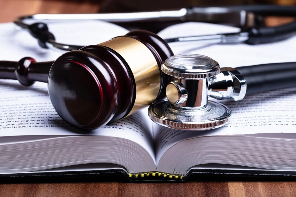 In the office of a Baltimore medical malpractice lawyer, a law book, a gavel, and a stethoscope rest together on a desk, symbolizing the foundational elements of a medical malpractice claim
