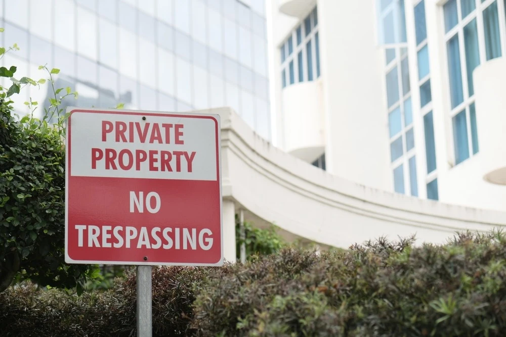 A "No Trespassing" sign looms at the forefront, symbolizing the deliberate acts of Intentional Torts that lead to personal injury